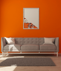 A living room with orange walls and grey couch.